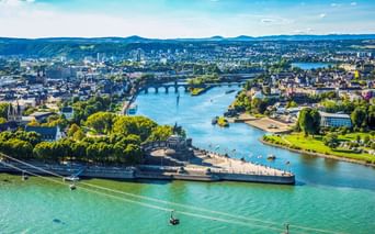 Luftaufnahme von Koblenz mit der Mündung von Rhein und Mosel am Deutschen Eck. Seilbahnen überqueren den Rhein, Brücken überspannen beide Flüsse.