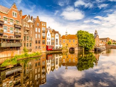 Historischer Kanal in Delfshaven, Rotterdam, gesäumt von traditionellen niederländischen Häusern, die sich im ruhigen Wasser spiegeln.