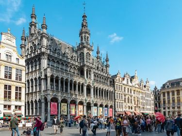 Rathaus Brüssel mit reich verzierter gotischer Fassade und hohem Turm am Grand Place, umgeben von historischen Gildehäusern und Touristenmassen.