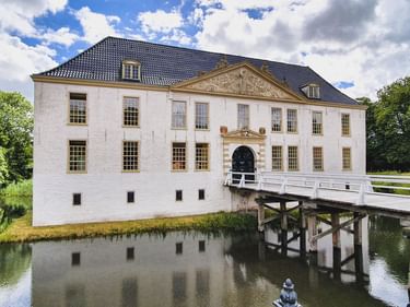 Wasserschloss Norderburg in Dornum, ein weißes barockes Wasserschloss mit blauem Dach, umgeben von Wassergraben und weißer Holzbrücke.