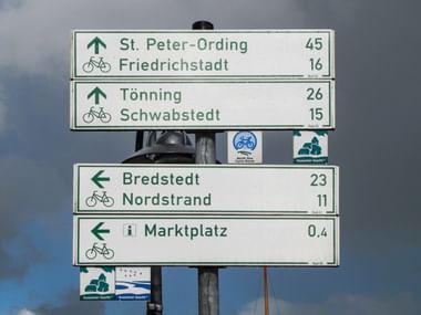 Radweg-Wegweiser mit Richtungen nach St. Peter-Ording, Friedrichstadt, Tönning, Schwabstedt, Bredstedt, Nordstrand und Marktplatz mit Entfernungen.