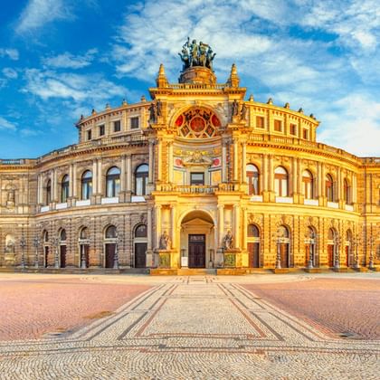 Die Semperoper in Dresden mit ihrer prächtigen Neorenaissance-Fassade im goldenen Sonnenlicht, mit Bogenfenstern und Skulpturen auf dem Dach.