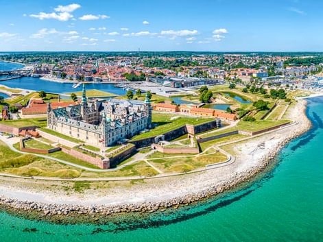 Luftaufnahme von Schloss Kronborg auf einer Halbinsel in Helsingør, Dänemark. Die Renaissancefestung ist von grünen Wällen und blauem Meer umgeben.