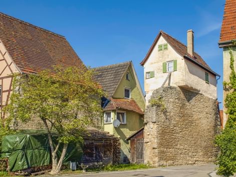 Historischer Lindleinturm aus Stein mit weißem Oberteil und grünen Fensterläden in Creglingen, umgeben von traditionellen Fachwerkhäusern.