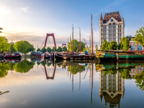 Historische Schiffe im Alten Hafen von Rotterdam mit ruhigen Wasserspiegelungen. Das Witte Huis und die Willemsbrücke sind im Hintergrund sichtbar.