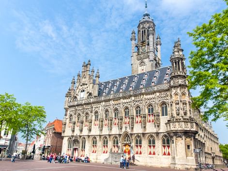 Das prächtige Stadhuis Rathaus in Middelburg mit gotischer Fassade, verzierten Türmen und rot-weißen Fensterläden. Besucher auf dem Platz.